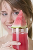 Woman holding glass of watermelon juice with watermelon wedge