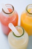 Three fruit juices in bottles with straws (overhead view)