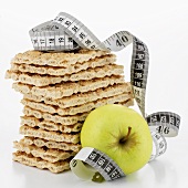 Crispbread, in a pile, and apple with tape measure