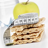 Crispbread with tape measure, apple in background