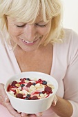 Woman holding bowl of yoghurt with berries & flaked almonds