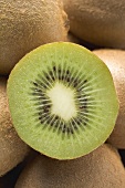 Half a kiwi fruit on several whole kiwi fruits (close-up)