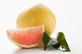 Whole grapefruit, wedge of pink grapefruit and leaves
