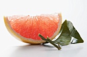 Wedge of pink grapefruit with leaves