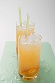 Two fruity drinks with kumquats and crushed ice