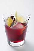 Red wine punch in glass with ice cubes and lemon