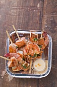 Salmon & prawn skewers with mint & sauce in aluminum dish