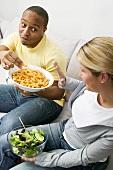 Couple on sofa with peanut puffs and salad
