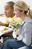 Couple in front of TV with pizza, salad and football