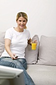 Woman with glass of orange juice watching TV