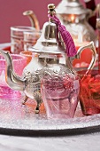 Silver teapot, glasses and windlights on tray