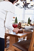 Woman putting cranberry sauce on Christmas table