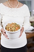Woman holding large dish of bread stuffing (Christmas)