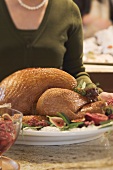 Woman with roast turkey in kitchen (Christmas)