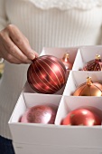 Woman taking red Christmas bauble out of box