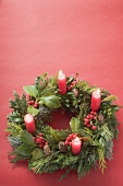 Advent wreath with four burning candles on red background