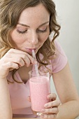 Woman drinking strawberry shake through straw