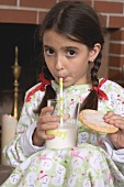 Girl drinking milk and holding biscuit