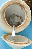 Coconut, shelled and hollowed out, with spoon