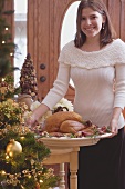 Junge Frau serviert gebratenen Truthahn zu Weihnachten