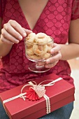 Woman reaching for almond biscuit in glass