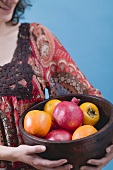 Woman holding fresh fruit in wooden bowl