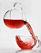 Pouring fruit tea from glass jug into cup