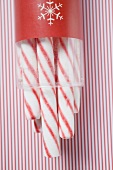 Candy canes in container on striped background