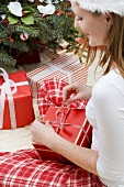 Frau mit Nikolausmütze öffnet Weihnachtsgeschenk
