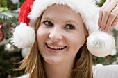 Woman in Father Christmas hat holding Christmas bauble