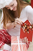 Frau mit Nikolausmütze steckt Weihnachtskarte in Briefkuvert