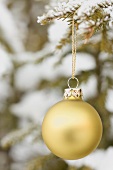Christmas bauble on snow-covered fir branch out of doors