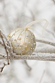 Christmas bauble on frost-covered branch out of doors