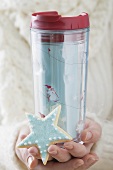 Woman holding star biscuit and insulated beaker