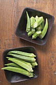 Several okra pods, whole & cut in two, in two dishes