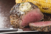 Peppered steak with herb butter and corn on the cob