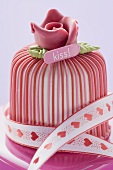 Marzipan-covered cake with ribbon on pink chocolate box