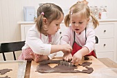 Two small girls cutting out chocolate biscuits