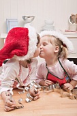 Zwei kleine Mädchen mit Nikolausmützen küssen sich in Küche