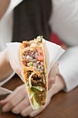 Woman holding mince taco in paper napkin