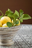 Fresh lemons with leaves in bowl