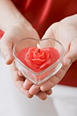 Hands holding heart-shaped windlight with rose candle