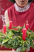 Frau bläst Kerzen auf Adventskranz aus