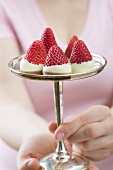 Woman holding chocolate-dipped strawberries on silver stand