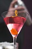 Cosmopolitan in glass, bartender in background