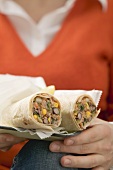 Frau hält Burritos mit Bohnenfüllung