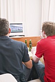 Two football fans watching football match on TV