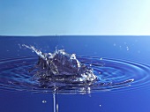 Splashing blue water creating concentric ripples