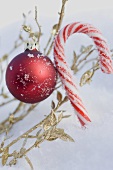 Christmas bauble and candy cane in snow