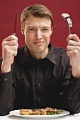 Man holding knife & fork with piece of beef steak on fork